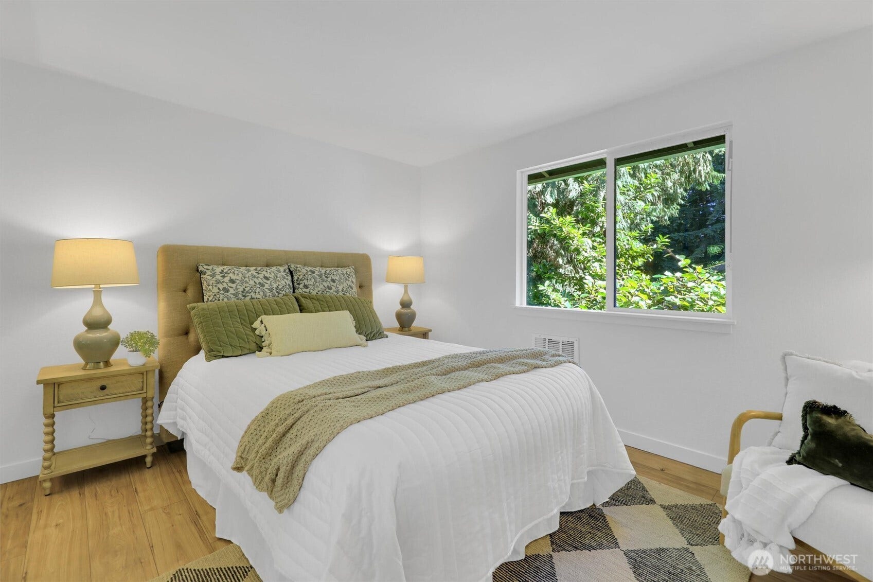 20915 W Richmond Road, Bothell, WA 98021 Comfortable bedroom with hardwood floors, upholstered bed, bedside tables, lamps, and a large window overlooking the trees.