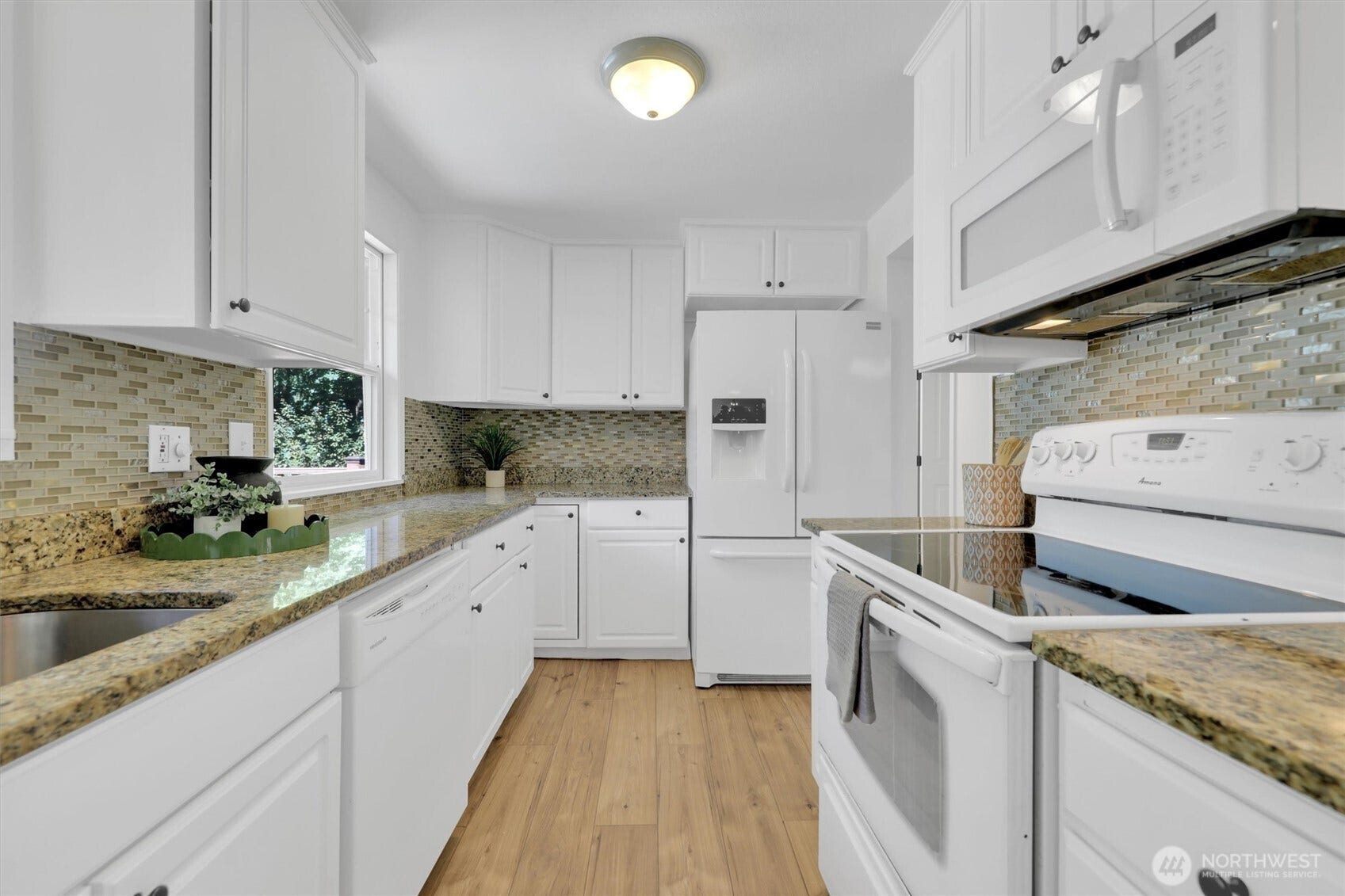 20915 W Richmond Road, Bothell, WA 98021 Bright white kitchen featuring granite countertops, mosaic tile backsplash, ample cabinetry, appliances, and hardwood flooring.