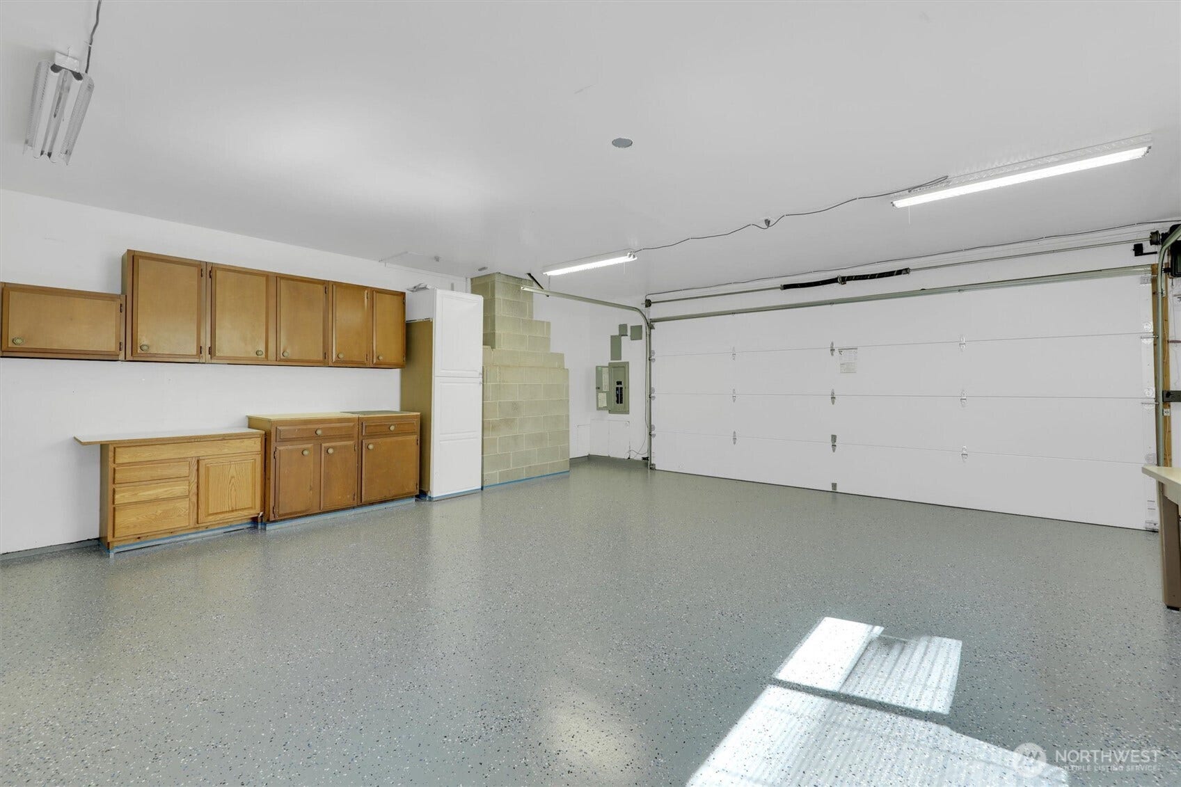 20915 W Richmond Road, Bothell, WA 98021 Large two-car garage featuring finished flooring, extensive wood storage cabinetry, overhead lighting, and a wide garage door.