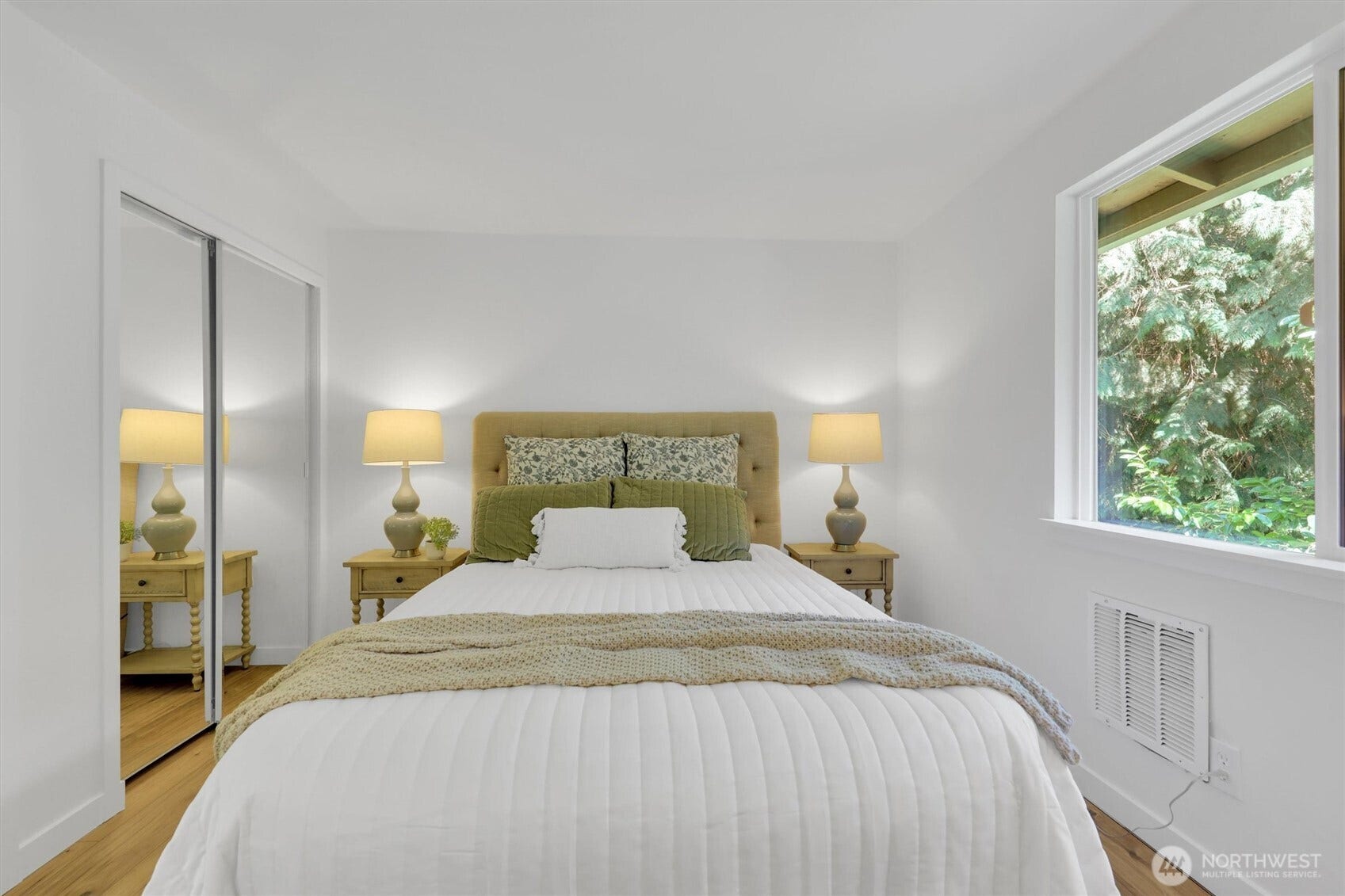 20915 W Richmond Road, Bothell, WA 98021 Primary bedroom featuring a neatly made bed, matching bedside tables and lamps, hardwood flooring, and a large window.