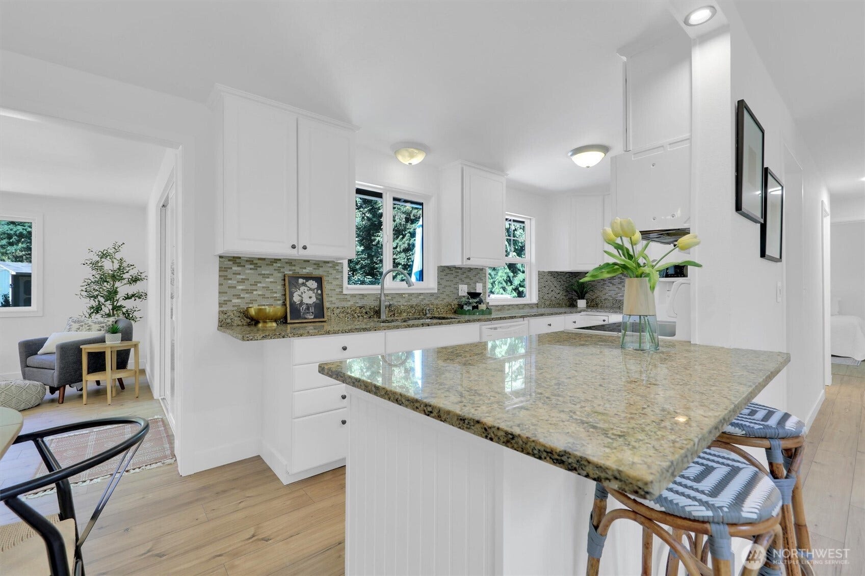 20915 W Richmond Road, Bothell, WA 98021 Updated kitchen with granite island, white cabinetry, tiled backsplash, breakfast seating, and an open connection to the dining and living areas.