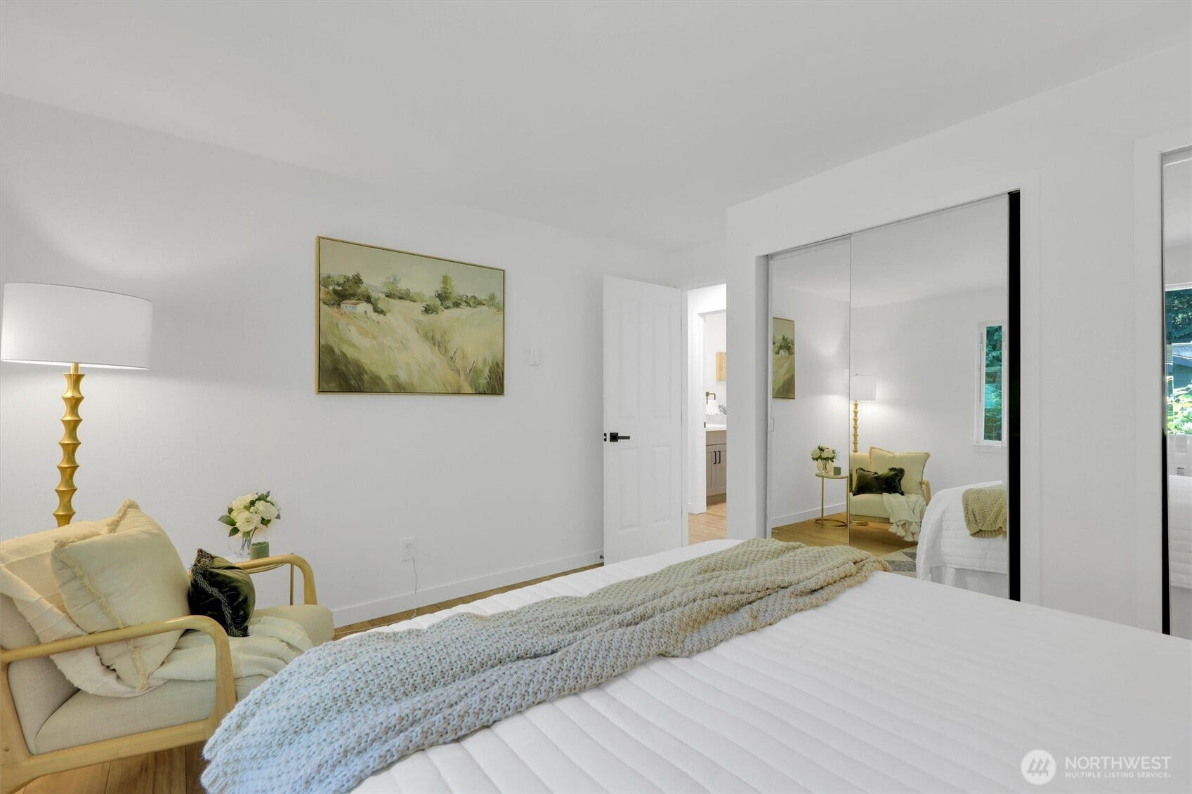 20915 W Richmond Road, Bothell, WA 98021 Bright bedroom with mirrored closet doors, hardwood floors, neutral furnishings, decorative artwork, and an adjoining hallway.