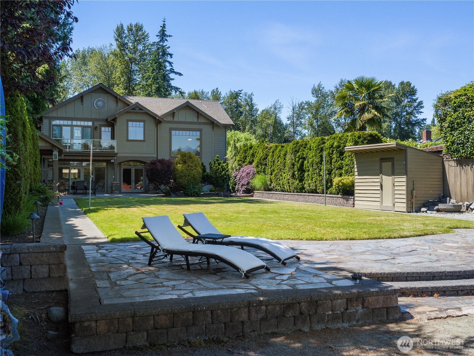 Enjoy the beauty of outdoor living with expansive lawn space, established landscaping, and a generous stone patio designed for relaxation and entertaining.
