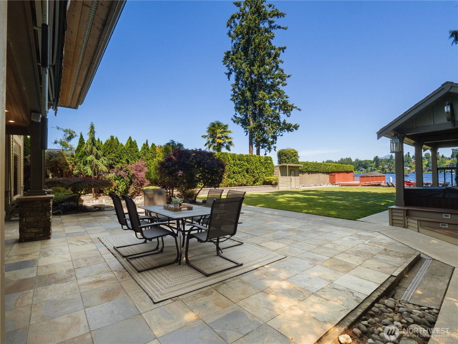 Designed for effortless indoor-outdoor living, this waterfront property features an expansive stone patio that extends into beautifully maintained grounds overlooking the lake.