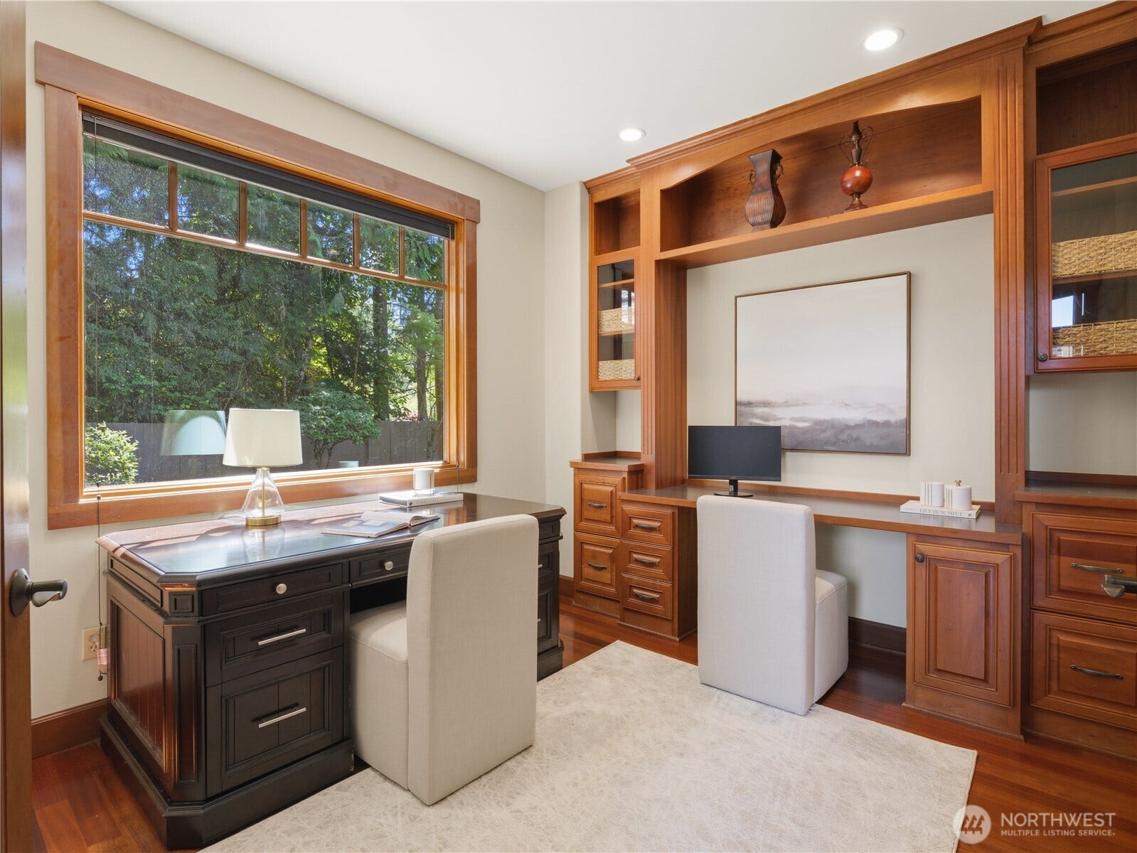 Thoughtfully crafted for productivity and comfort, the office showcases custom millwork, built-in cabinetry, and a spacious workstation framed by a large window overlooking the grounds.
