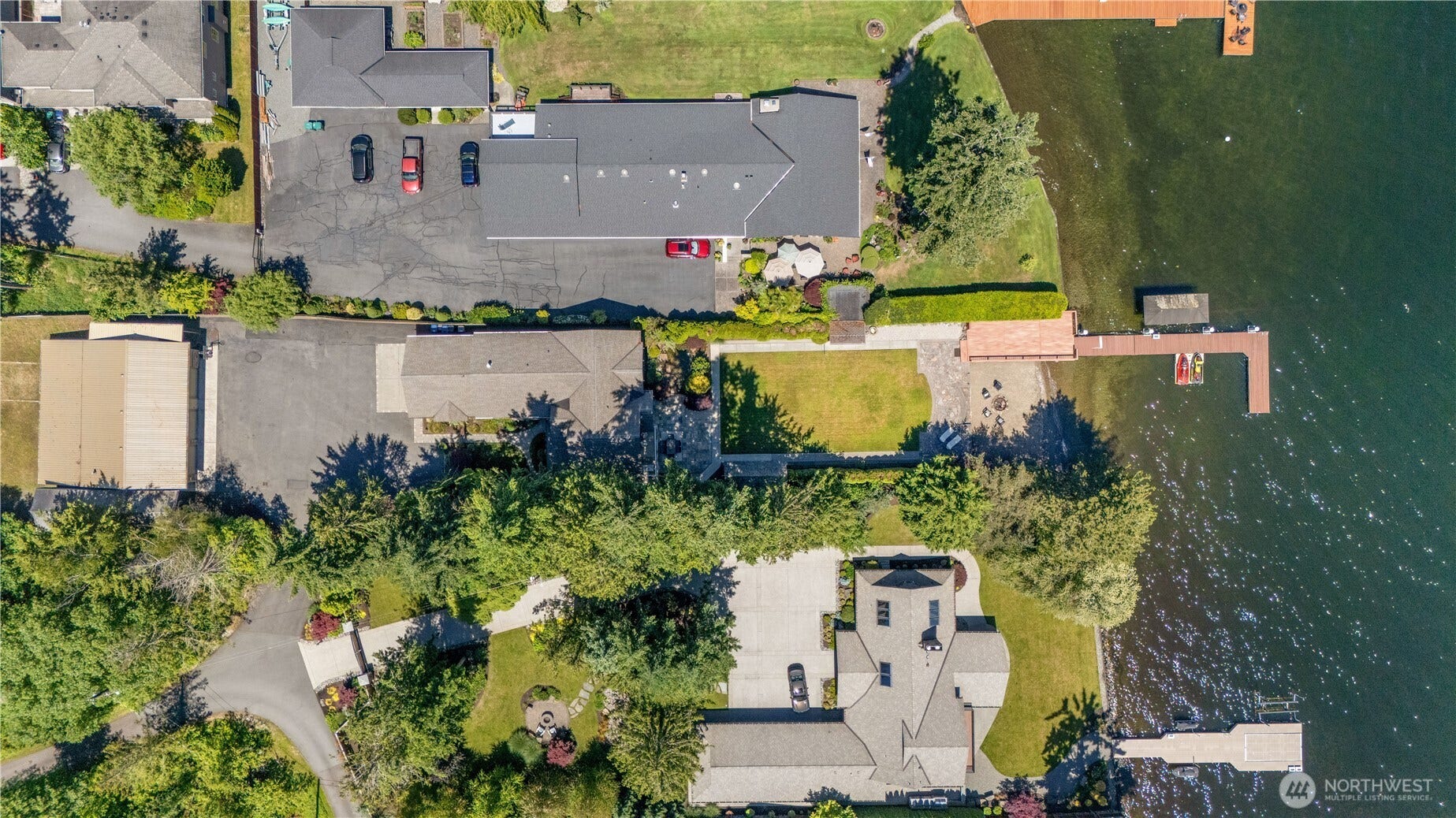 An aerial view showcases the property's rare combination of private waterfront, expansive grounds, and a detached garage/shop offering exceptional flexibility for storage, recreation, and hobbies.