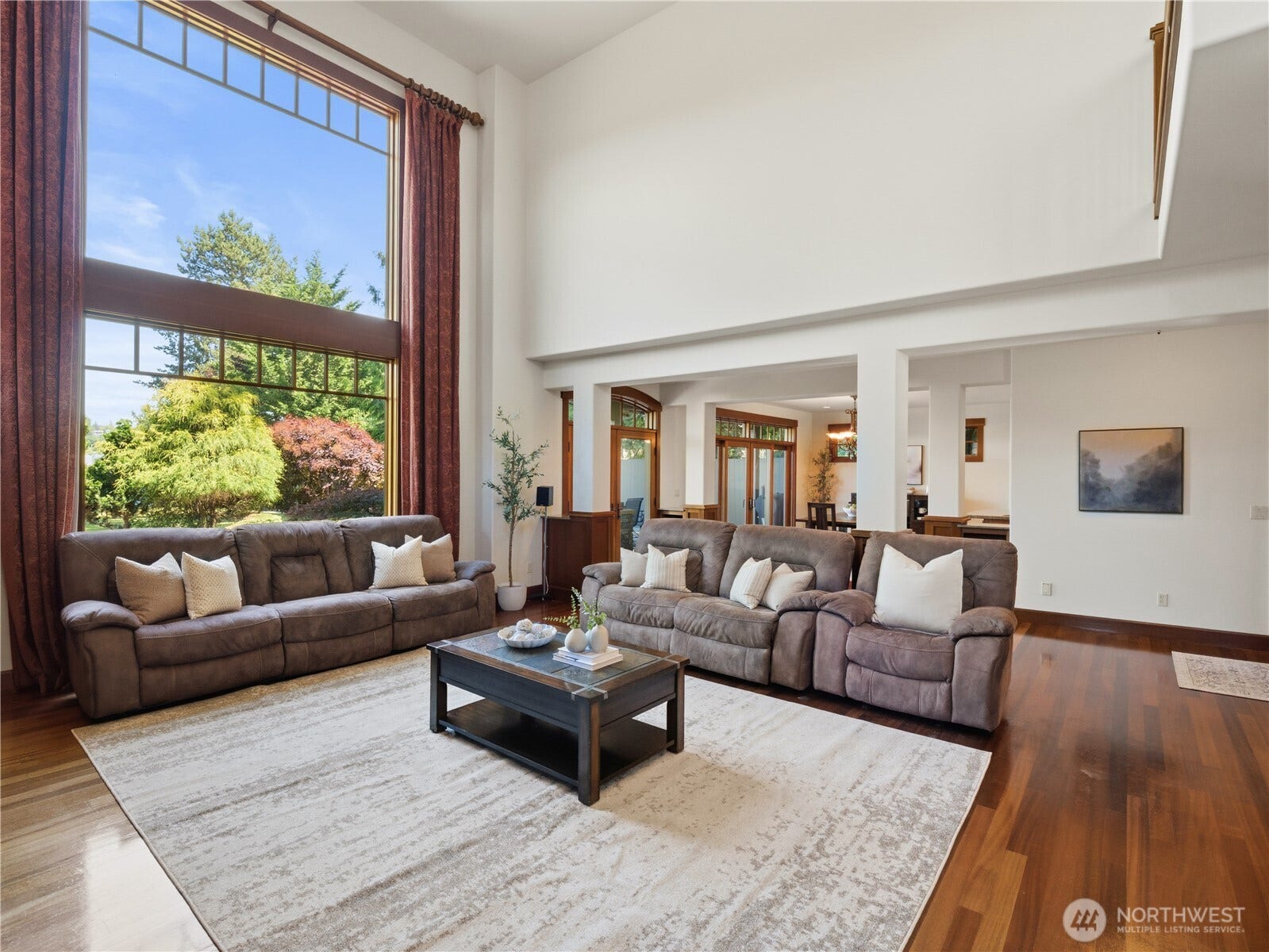 Dramatic ceiling heights and expansive windows define this spacious great room, filling the space with natural light and showcasing beautiful outdoor views.