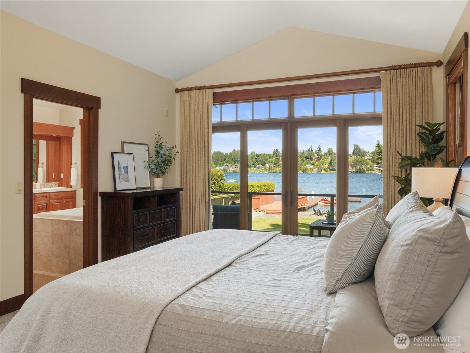 Wake up to water views from this spacious primary suite featuring large windows, vaulted ceilings, and direct access to a private balcony.