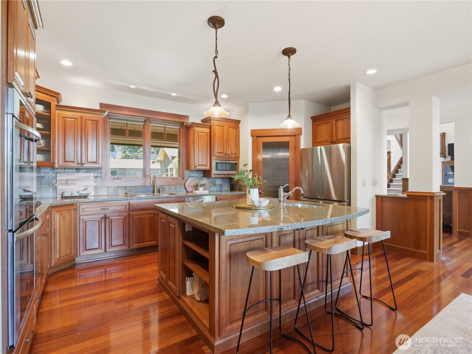 Designed with both everyday living and entertaining in mind, the kitchen features granite countertops, a substantial center island, stainless steel appliances, and abundant cabinetry.