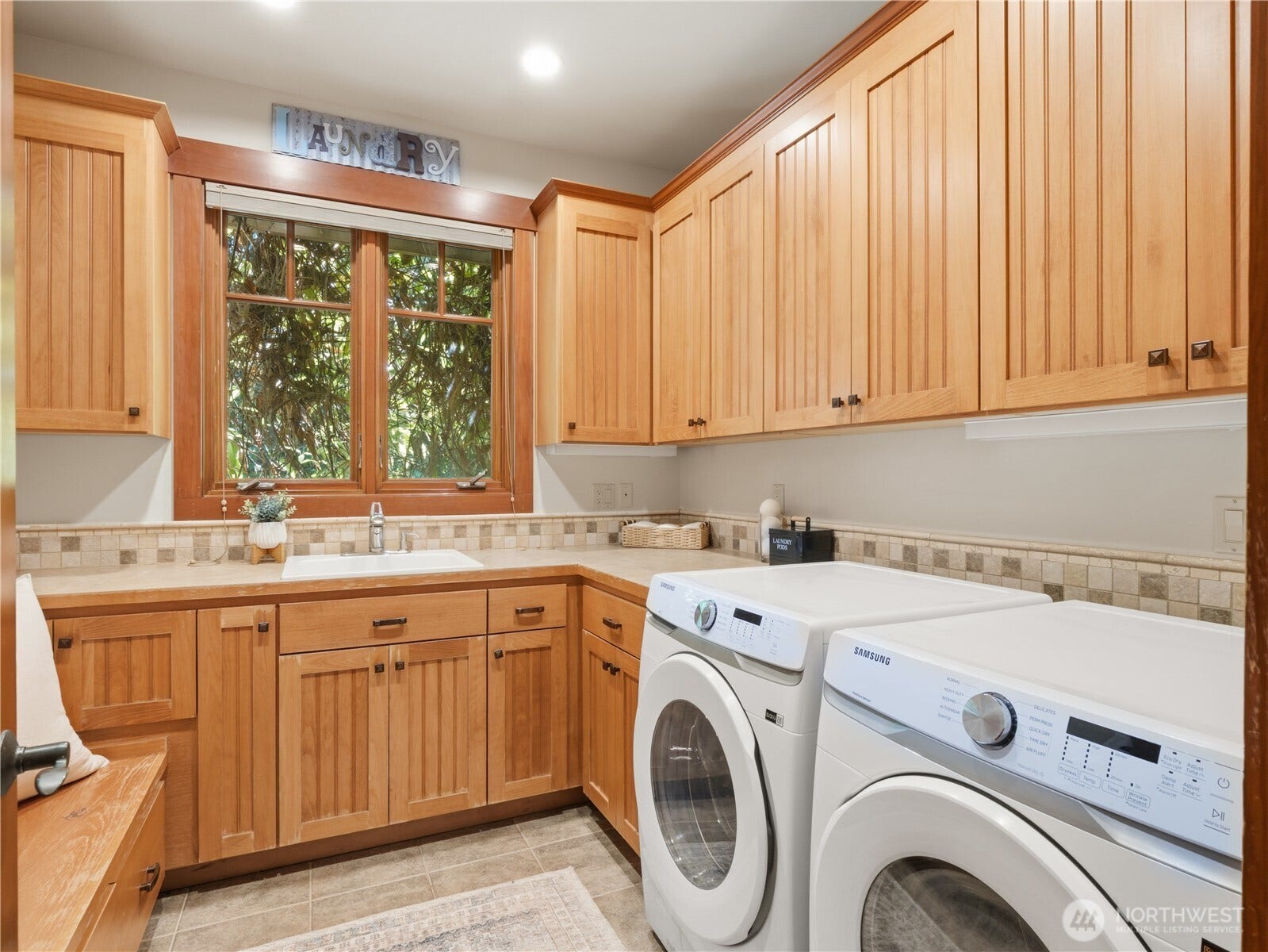 Spacious utility room featuring extensive custom cabinetry, generous counter space, utility sink, and dedicated laundry area.