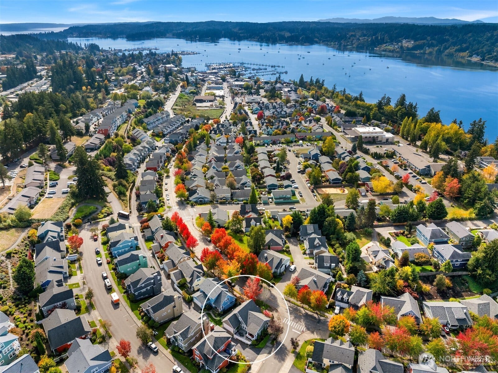 19800 Jensen Way NE, Poulsbo, WA 98370 This aerial perspective highlights the homes setting within Poulsbo, with the waterfront, marina, and surrounding town stretching toward the wooded shoreline beyond.