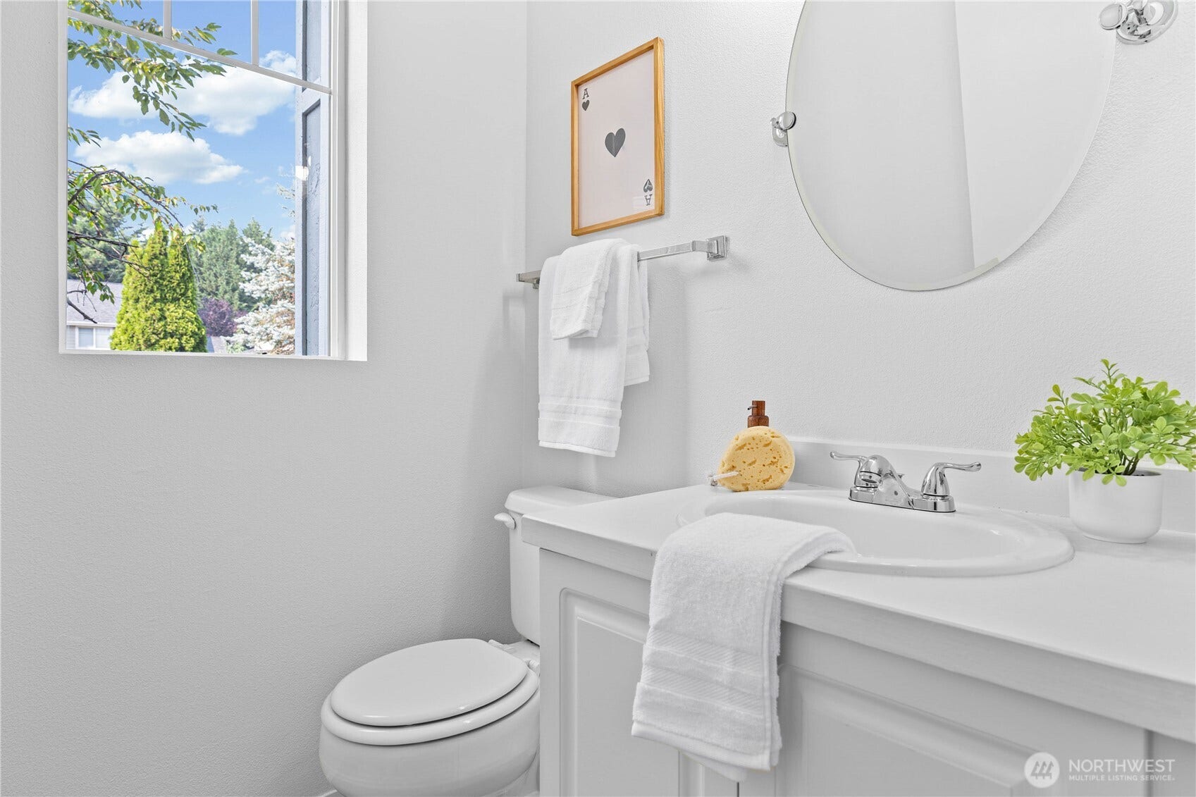 The main-level powder room features a crisp neutral palette, classic vanity, and a large round mirror for a clean, timeless look.