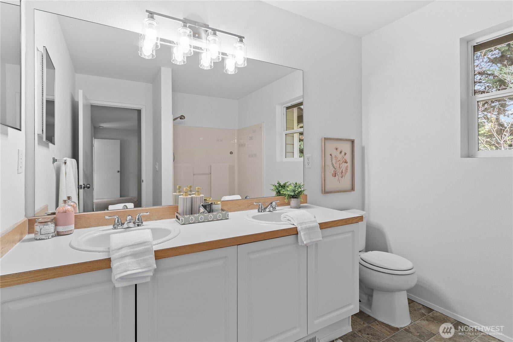 The Primary Suite's bath features a spacious dual-sink vanity with generous counter and cabinet space, making busy mornings easier. The large mirror and timeless lighting enhance the bright, functional design.