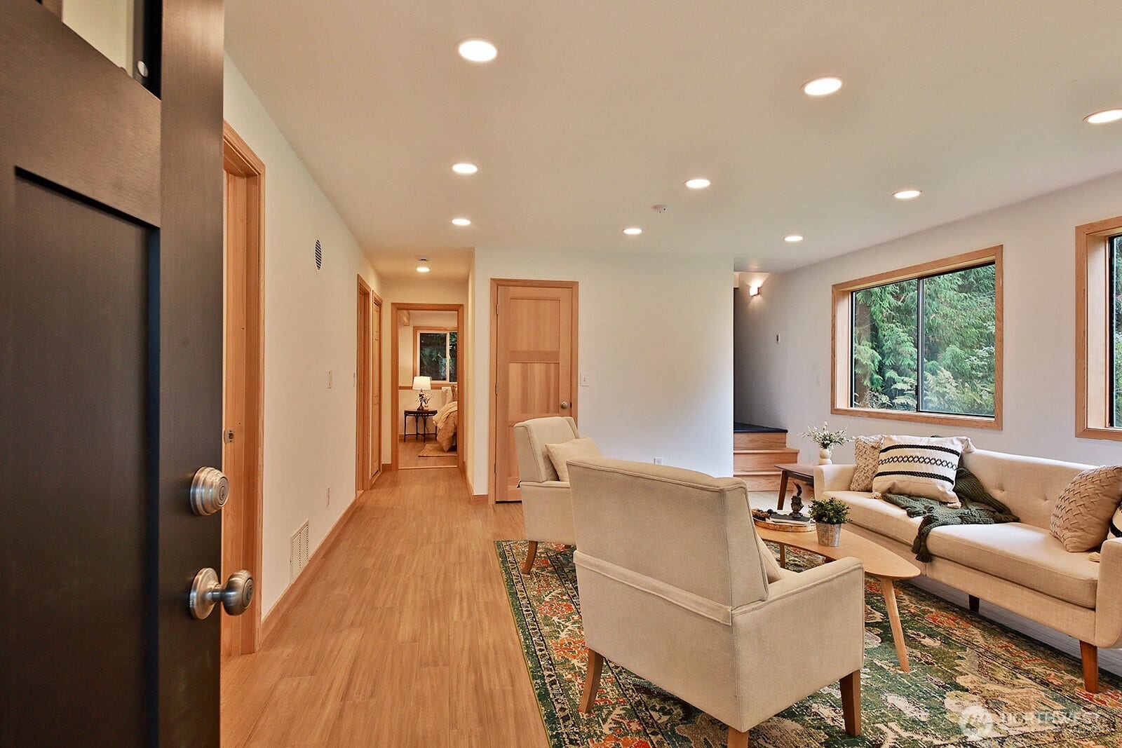 We are now on the lower level and entering through a separate entry. Interior stairs are visible along the right edge of the photo beyond the windows. Straight ahead to Primary Suite. Office & Laundry are through the open door just beyond the open main door.