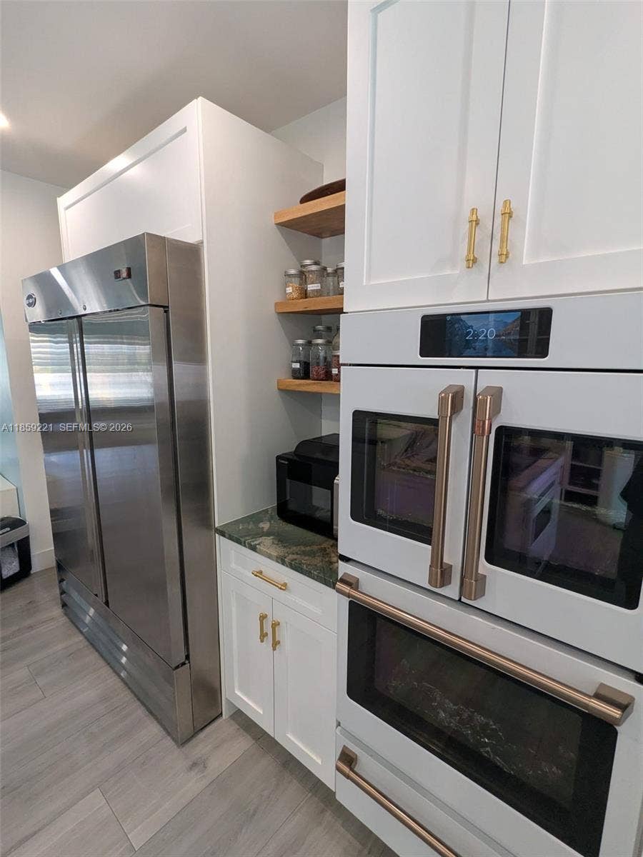 524 NE 27th Drive, Wilton Manors, FL 33334 Refined white-finish double oven and floating shelves add a touch of elegance and sophistication to the kitchens overall design.