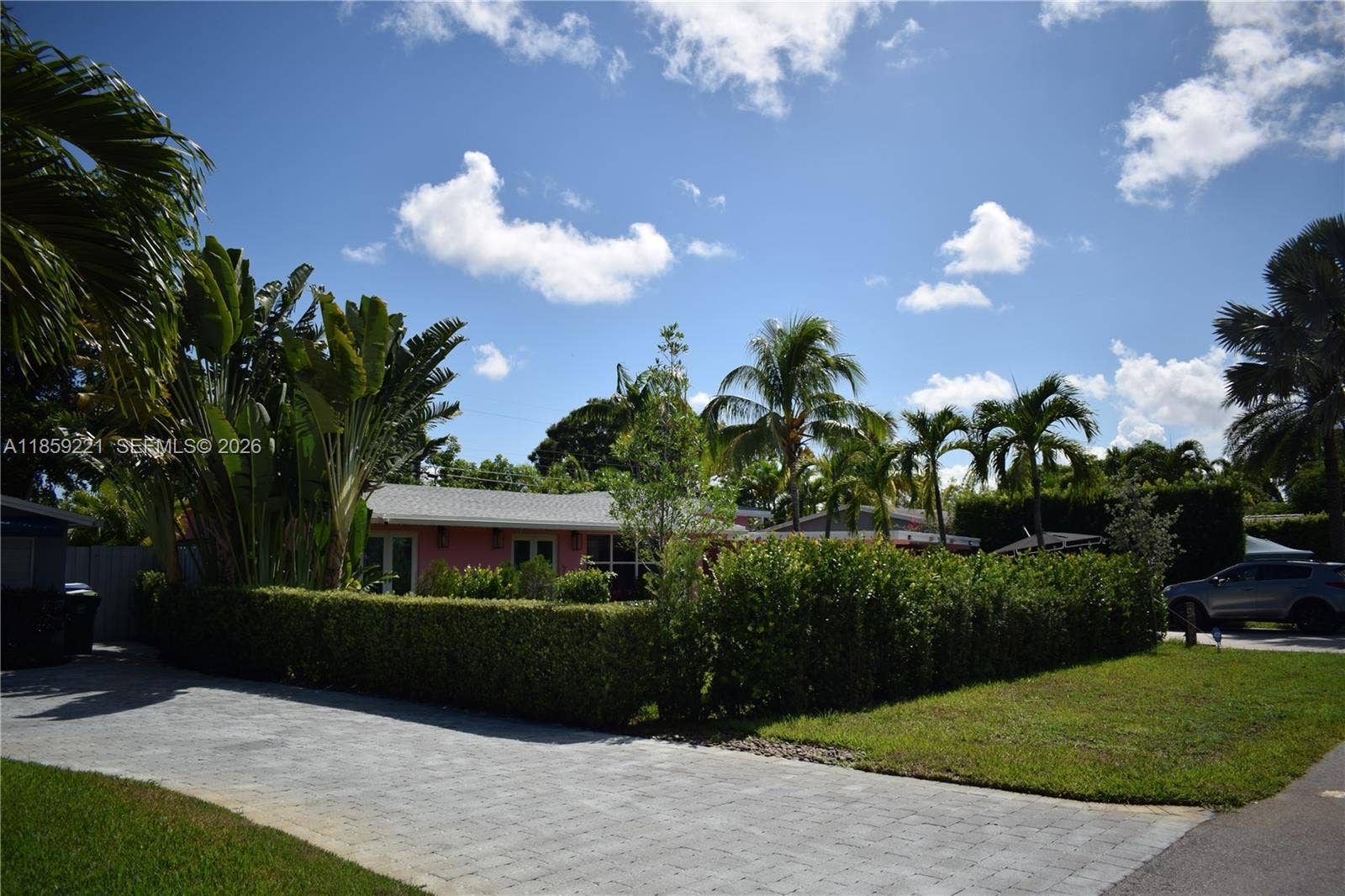 524 NE 27th Drive, Wilton Manors, FL 33334 Exterior view features a hedge-lined fence with integrated lighting for privacy and ambiance
