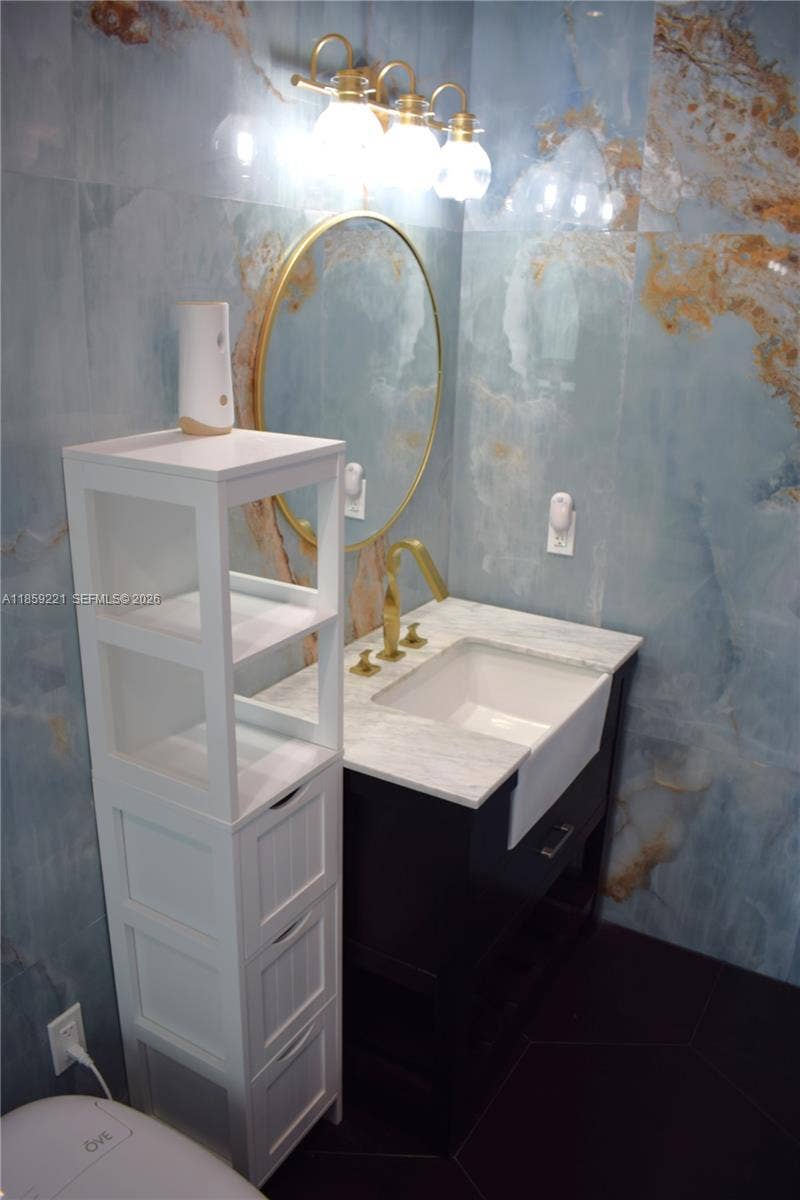 524 NE 27th Drive, Wilton Manors, FL 33334 Beautiful private bathroom showcasing vibrant blue and golden tiles carefully crafted for a seamless luxurious design, and deep sink with front exposure to enhance your daily routines.