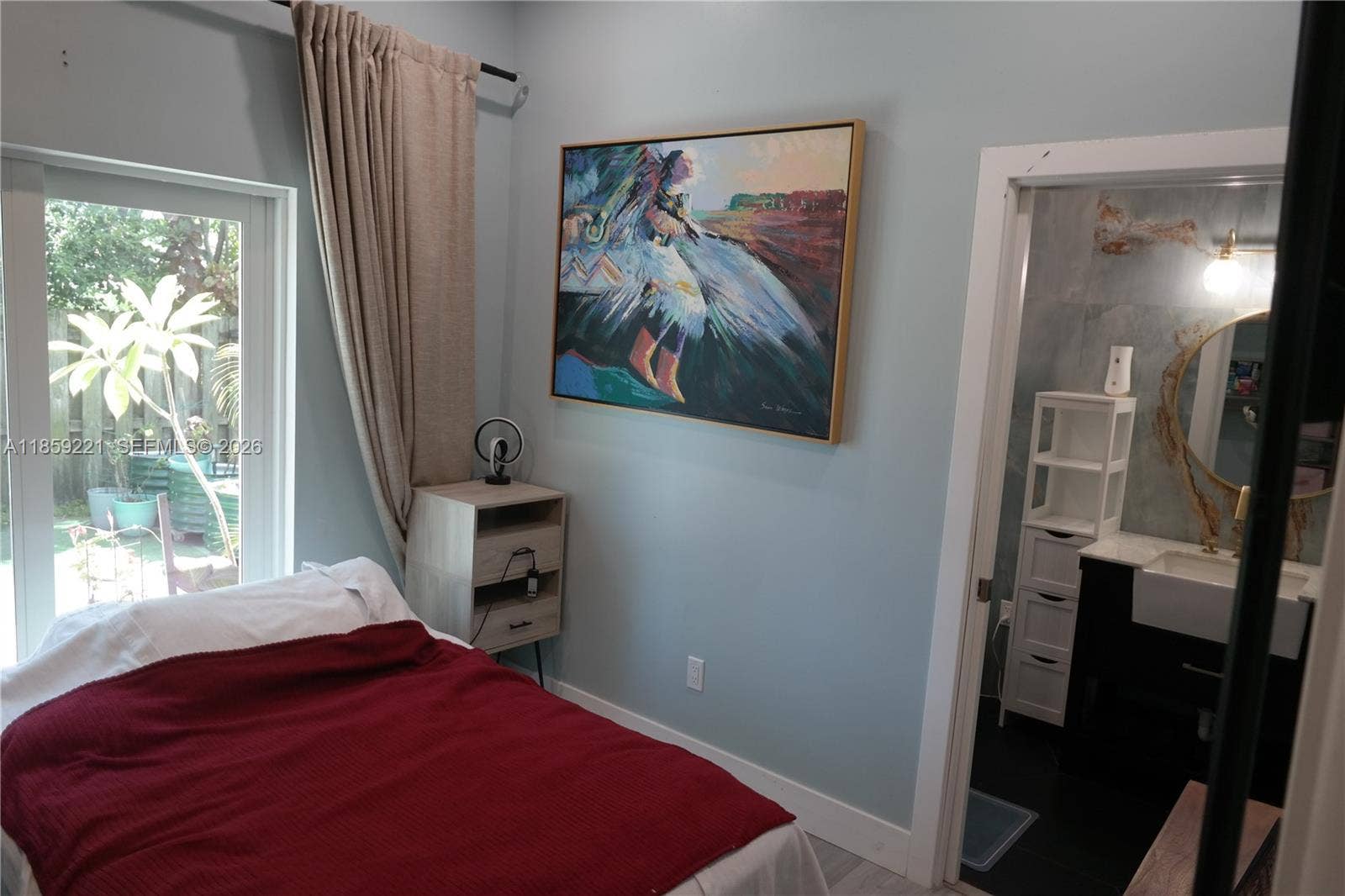 524 NE 27th Drive, Wilton Manors, FL 33334 Bedroom with sliding doors for direct access to the back patio and a stunning private bathroom clad in striking sky-blue design.