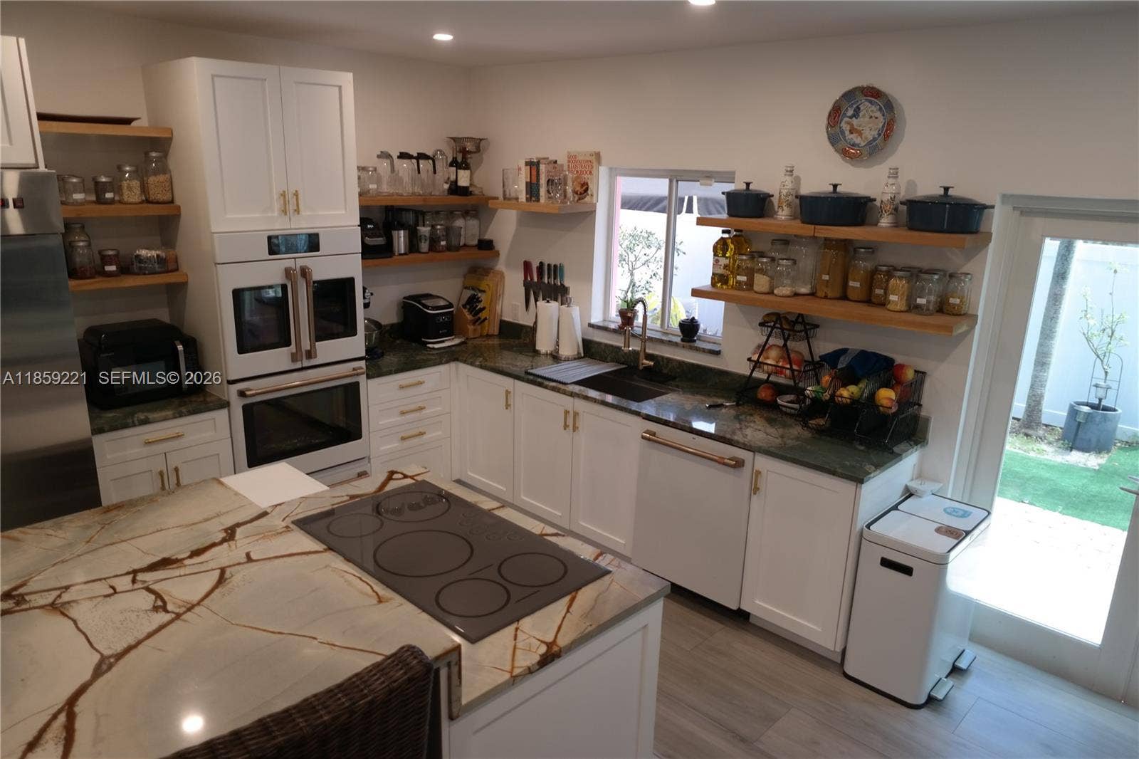 524 NE 27th Drive, Wilton Manors, FL 33334 Stunning glass cooktop seamlessly complements the two-tier waterfall island, creating a sleek and sophisticated centerpiece