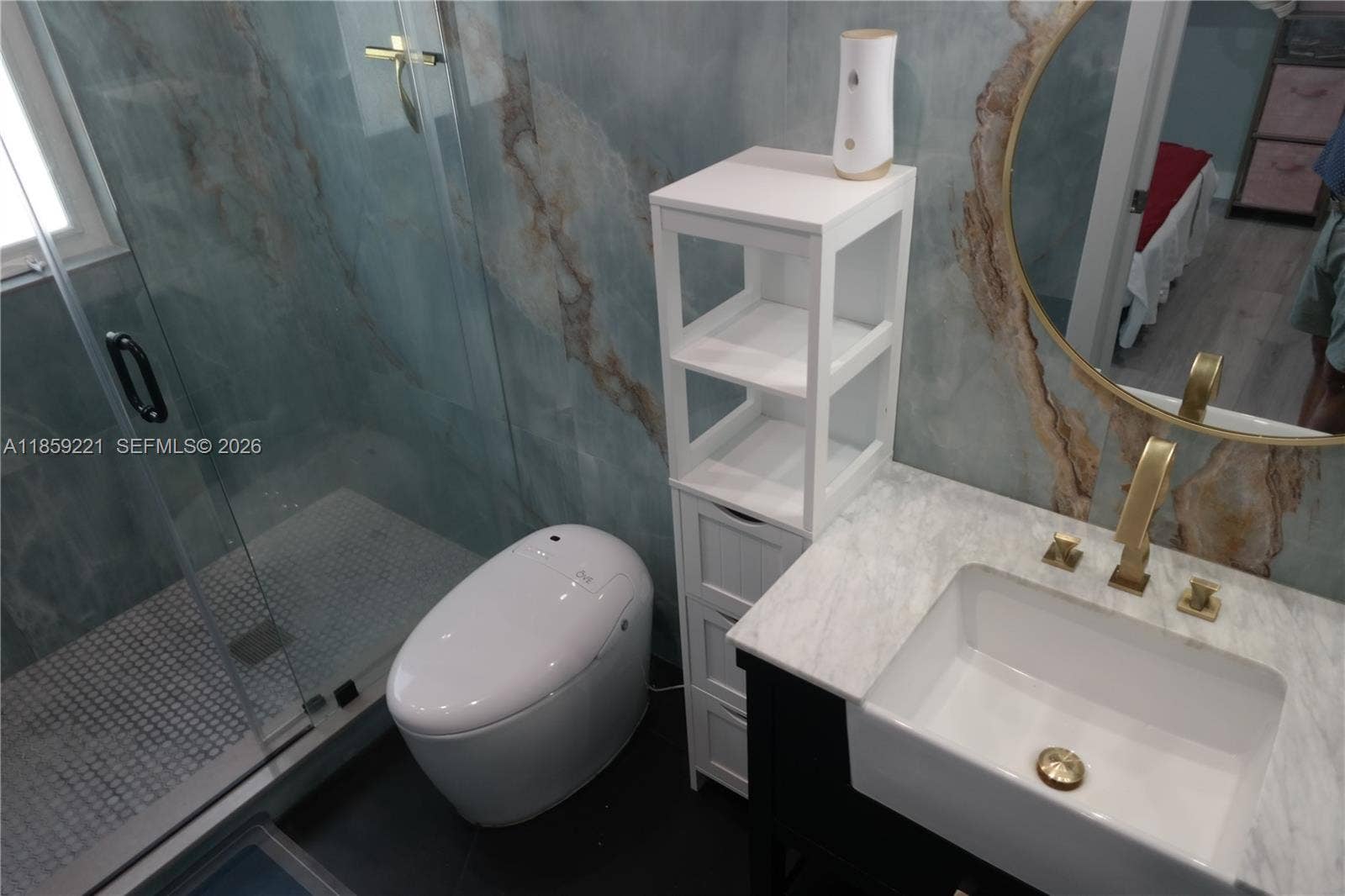524 NE 27th Drive, Wilton Manors, FL 33334 Elegant en-suite bath clad in bold light-blue and golden tiles, with a large, low-threshold shower designed for comfort and style.