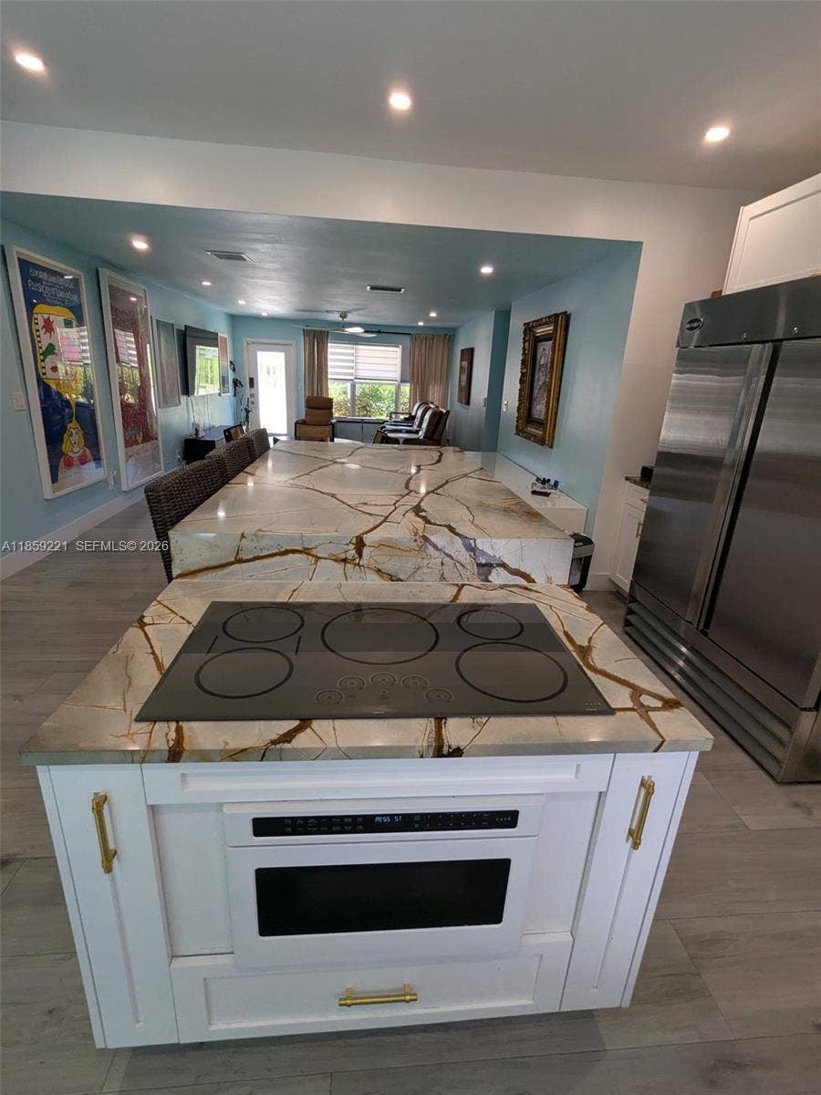 524 NE 27th Drive, Wilton Manors, FL 33334 Coordinated white fixtures blend seamlessly with the cabinets, accented by charming handles and light fixtures that highlight their appeal.