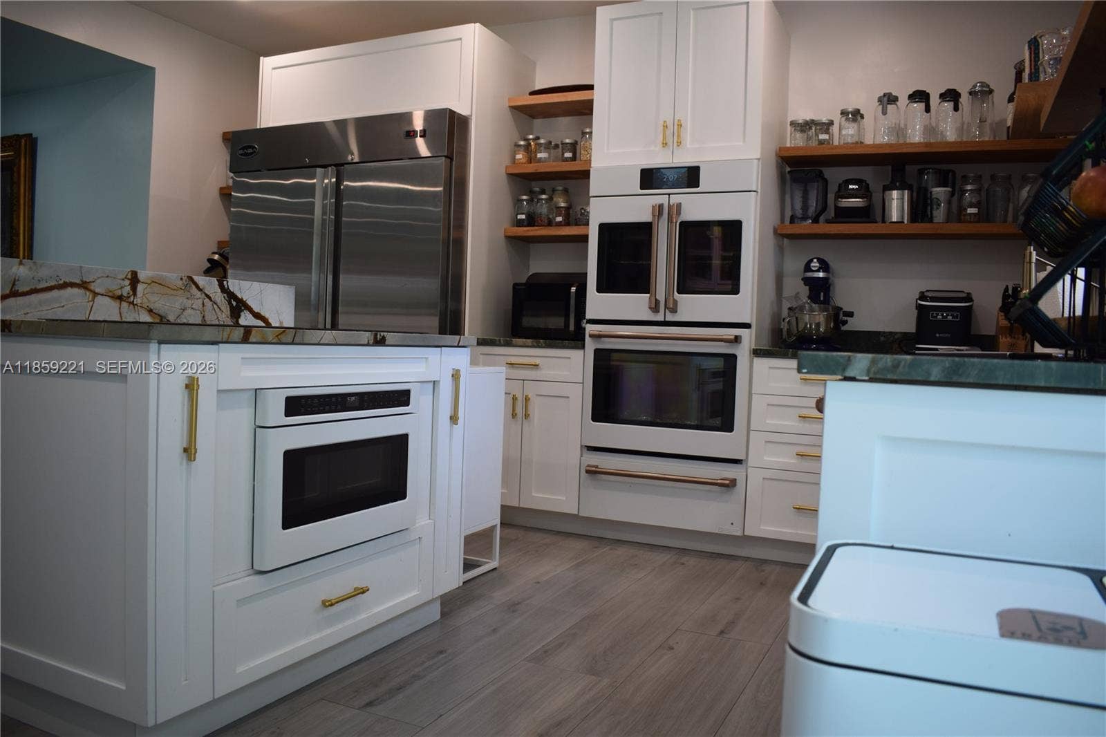 524 NE 27th Drive, Wilton Manors, FL 33334 All-white appliances perfectly complement the cabinetry, while elegant golden hardware enhances their beauty.