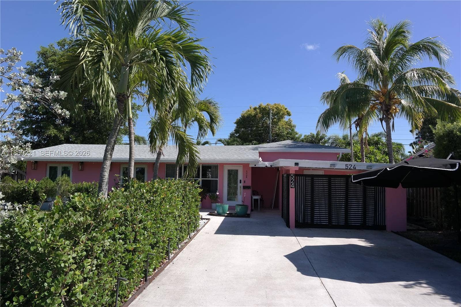 524 NE 27th Drive, Wilton Manors, FL 33334 New 2023 roof, all high impact windows and doors, and a spacious spotless front driveway, surrounded by tall, graceful palms and green walls.