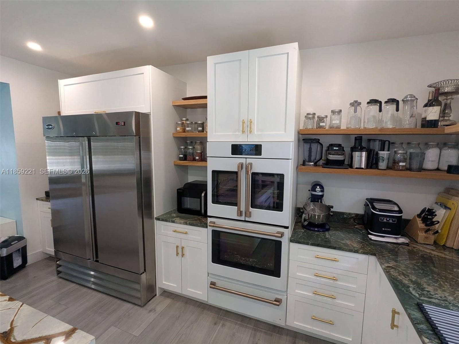 524 NE 27th Drive, Wilton Manors, FL 33334 Charming kitchen and oversized Saba double-door stainless steel fridge with warm, coordinated lighting that creates a cozy atmosphere.