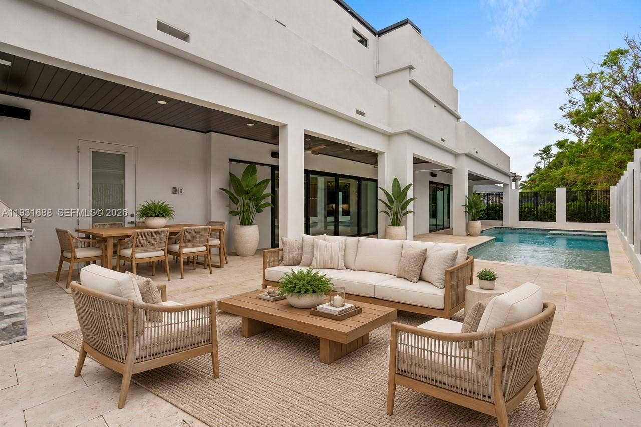 Covered patio featuring stone tile flooring, recessed ceiling lighting, a built-in outdoor kitchen station, and a swimming pool with stone surround