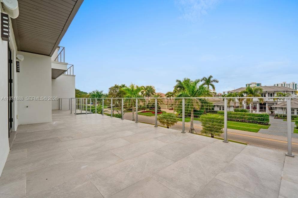 Expansive balcony featuring large-format stone-finish tiling, cable railing system, and a recessed ceiling with integrated exterior lighting