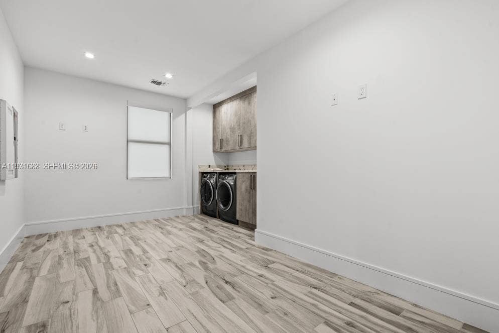 Laundry room featuring wood-finish flooring, built-in cabinetry, stone-surface countertop, and recessed lighting