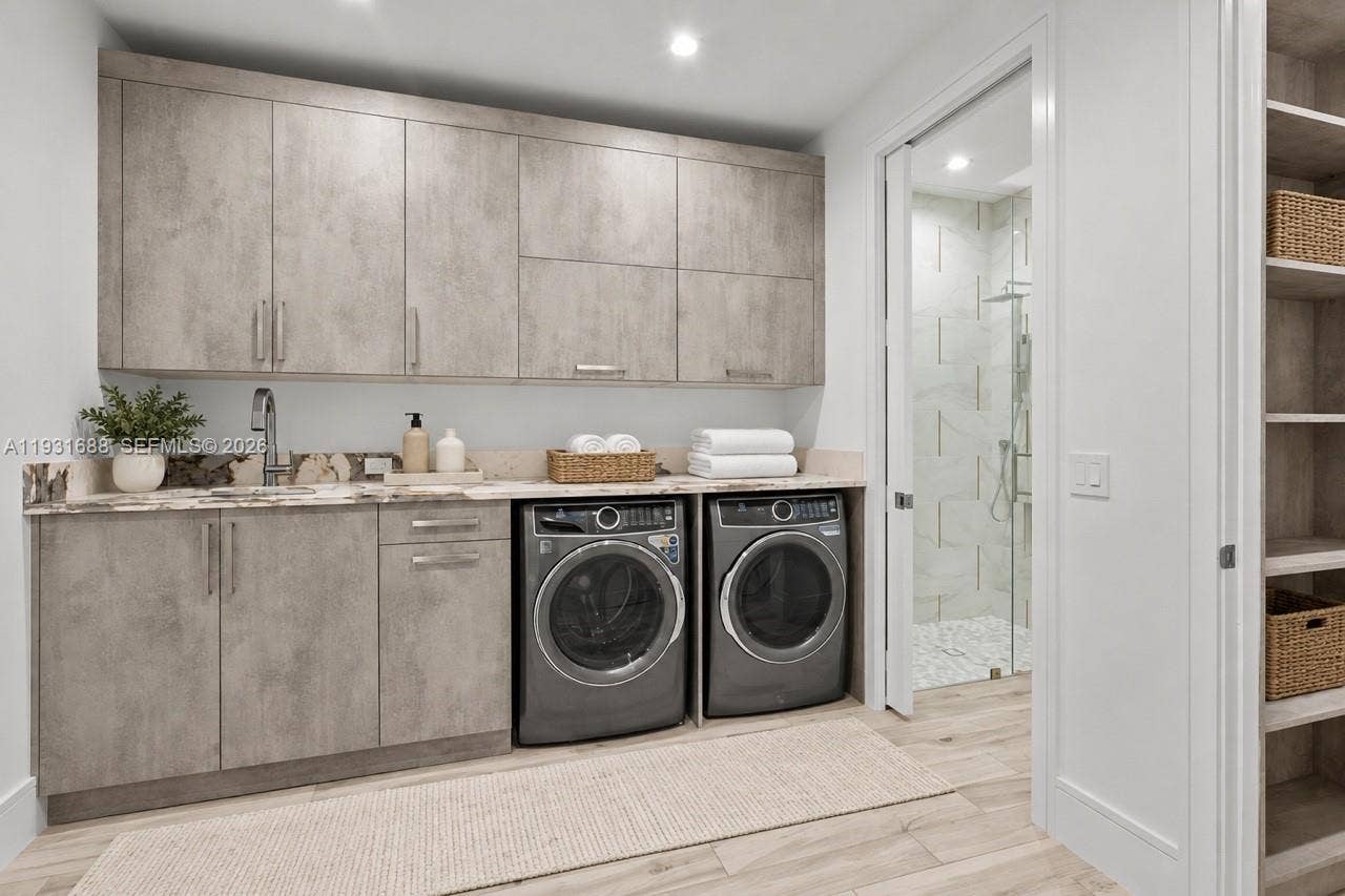 Laundry area featuring textured cabinetry, stone-surface countertop with an integrated sink, wood-finish flooring, and built-in shelving