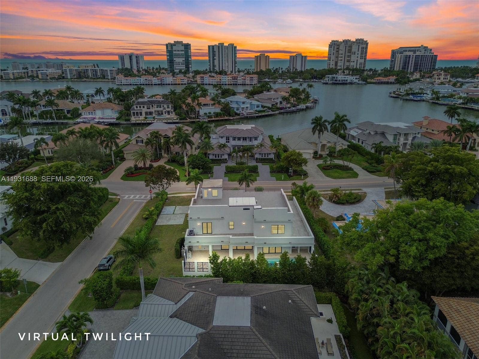 Aerial view of a coastal property featuring a multi-level architectural exterior, a private rear swimming pool, manicured landscaping, and direct water frontage