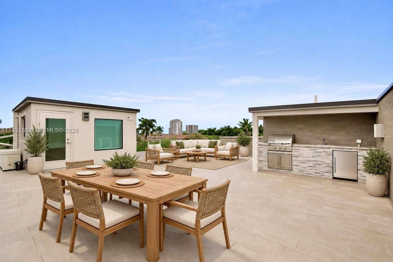 Rooftop terrace featuring large-format tile flooring, a built-in outdoor kitchen with stone veneer cladding, stainless steel appliances, and a sheltered area