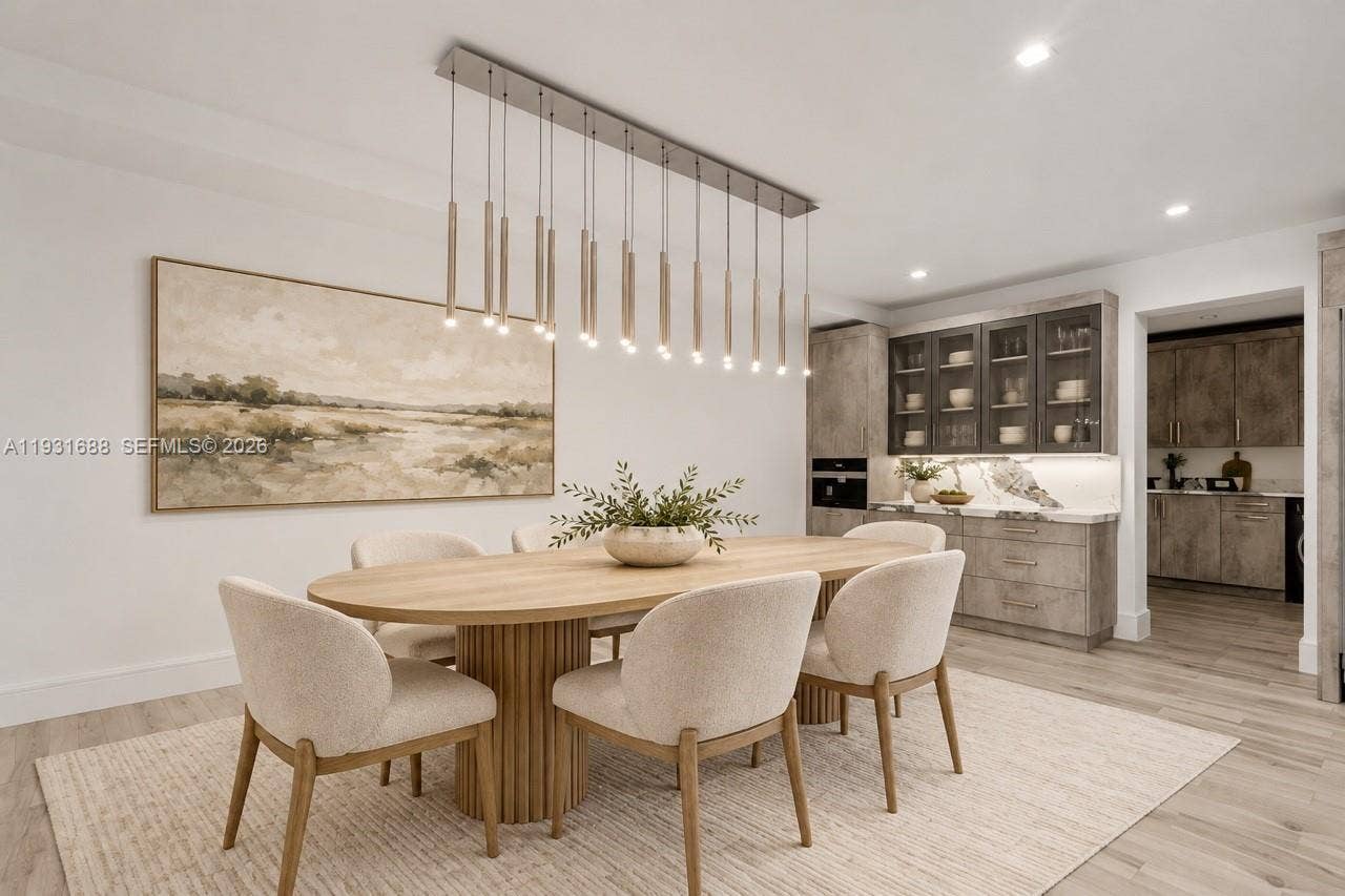 Multi-light linear pendant fixture, built-in cabinetry with glass-front uppers, stone-finish backsplash, and wood-finish flooring