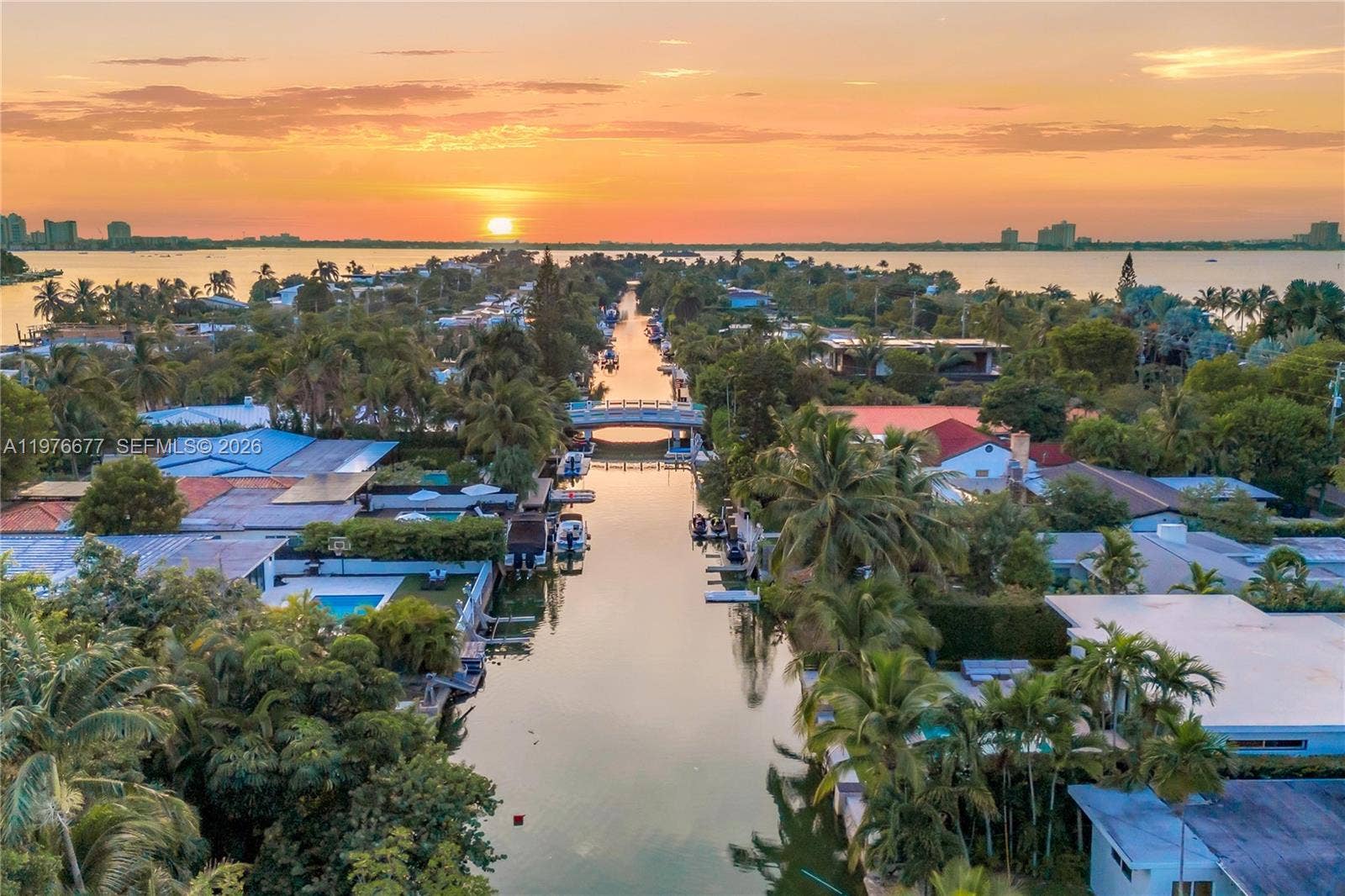 Aerial perspective of waterfront properties featuring deep-water canal access, private boat docks, mature palm trees, and residential architecture situated along the coastline
