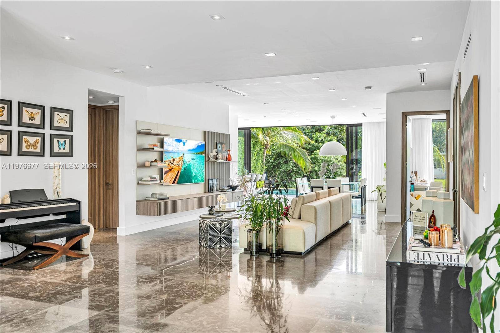 Open-concept interior featuring polished stone flooring, recessed lighting, and a custom wall-mounted media console with built-in shelving