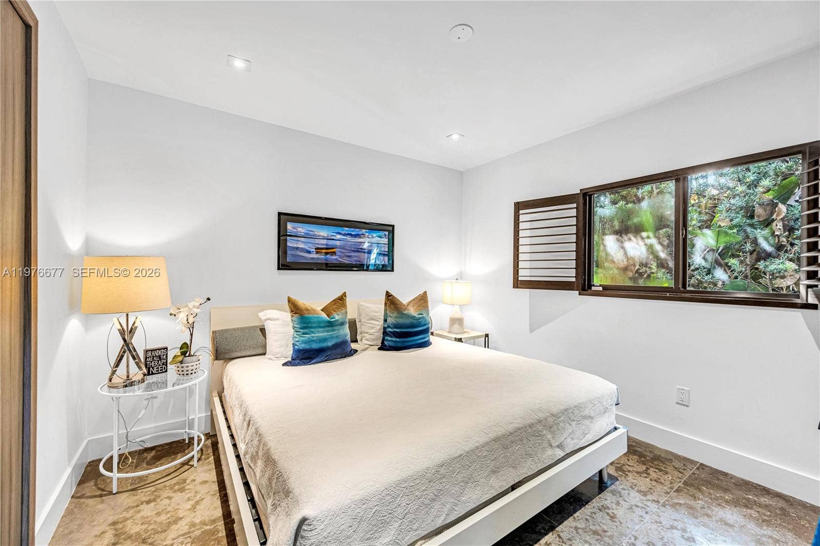 Neutral-toned tile flooring, recessed ceiling lighting, and horizontal window shutters featuring exterior greenery