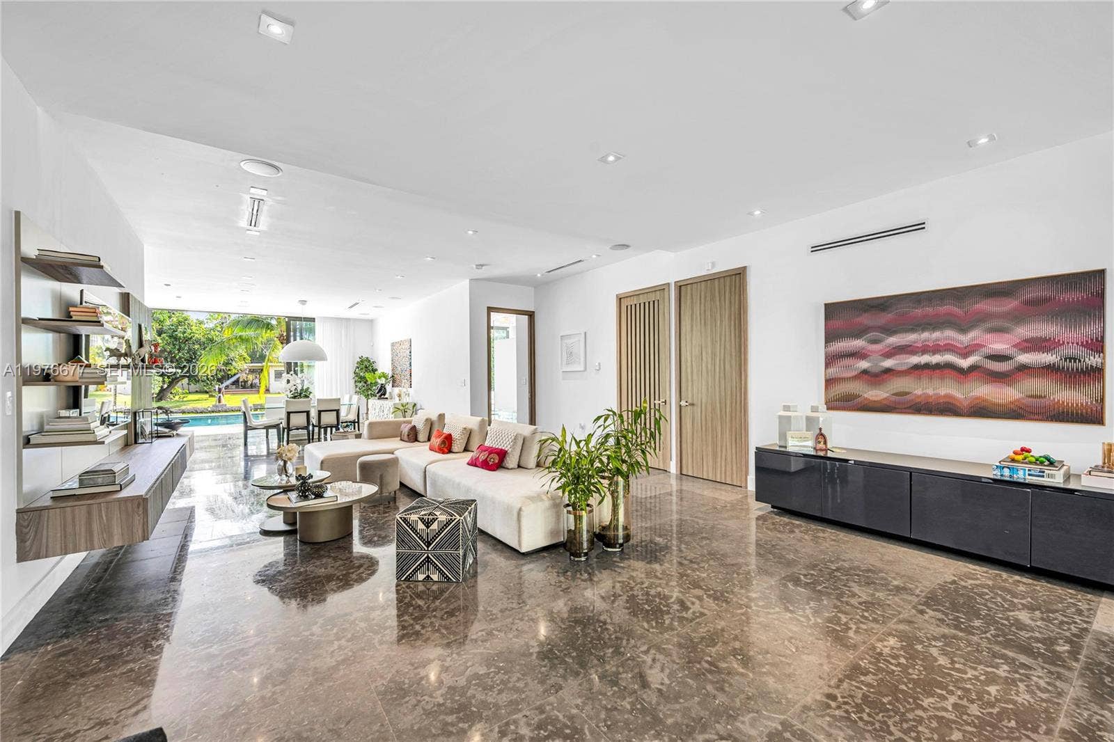 Polished stone flooring, recessed ceiling lighting, wall-mounted wood-finish cabinetry, and full-height interior doors