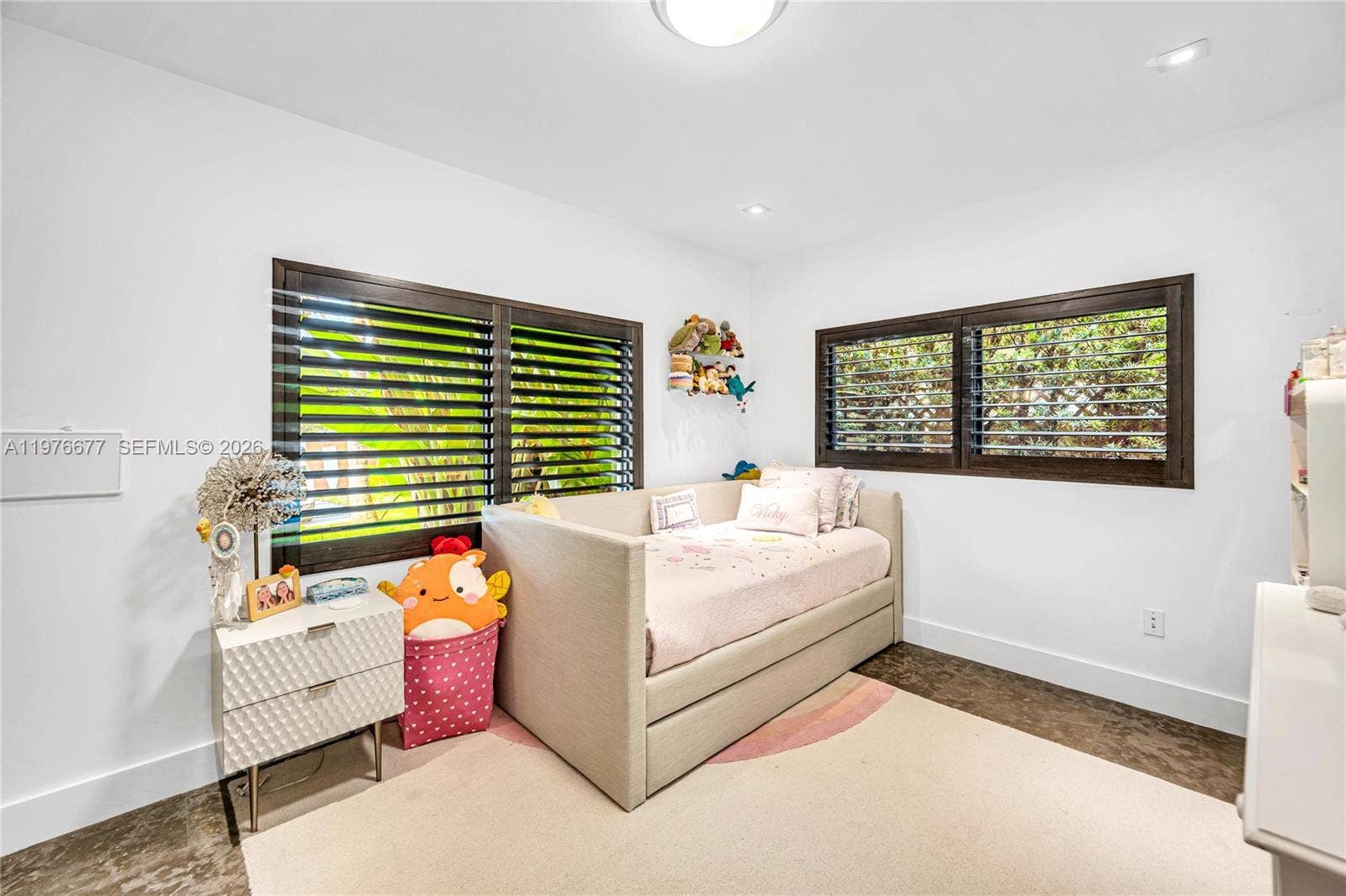 Room featuring dark wood-finish flooring, white walls, recessed ceiling lighting, and large windows with dark wood shutters