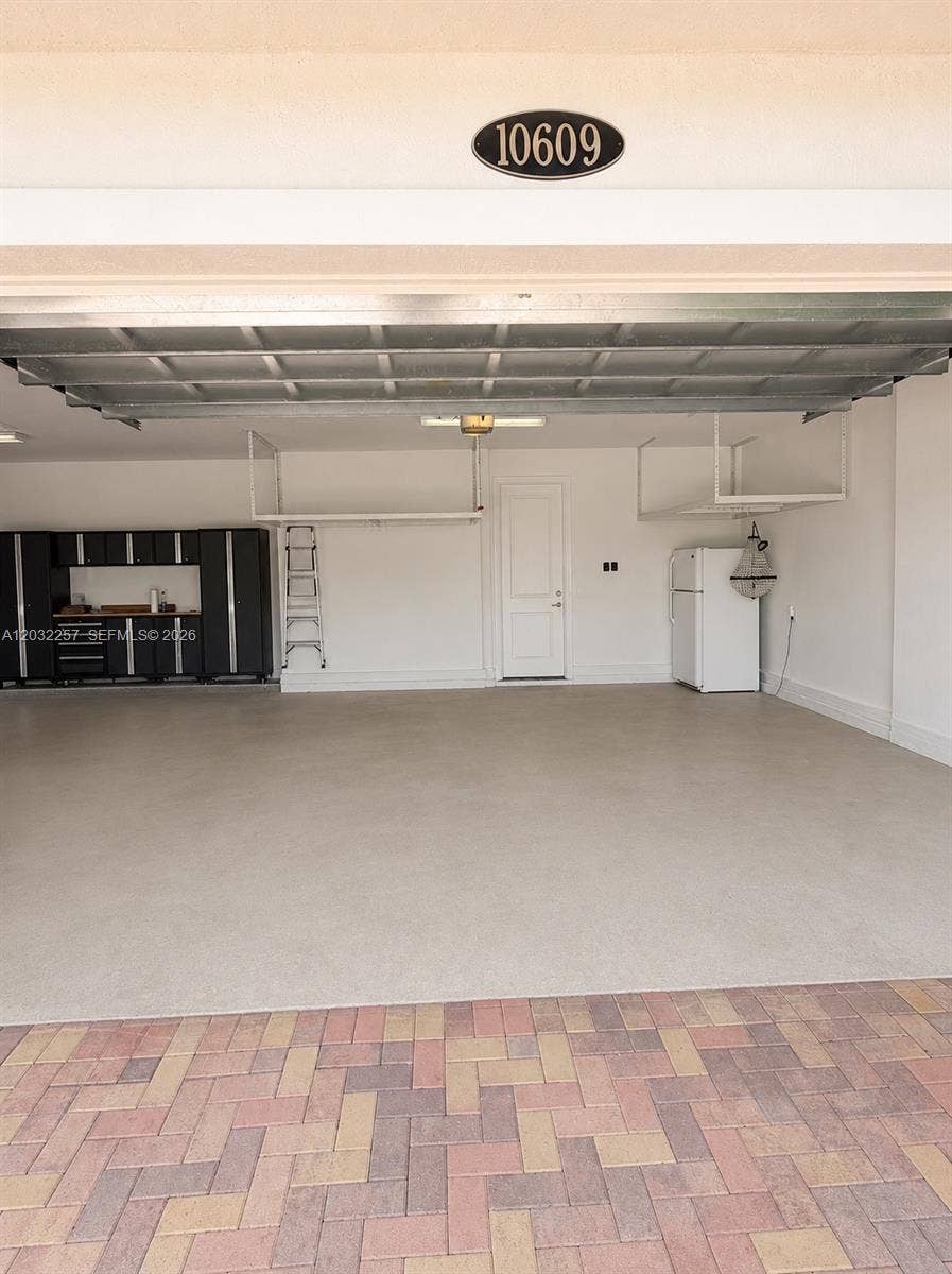 GARAGE DOUBLE DOOR SIDE. CUSTOM CABINET WALL AND DOUBLE CEILING RACKS. ALSO A REFRIGERATOR WITH FREEZER.