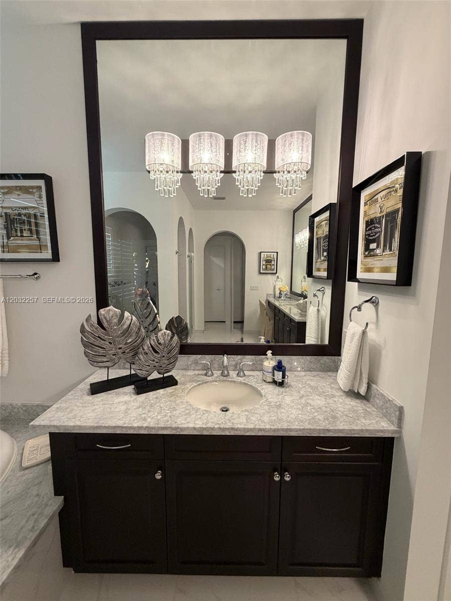 SMALLER OF TWO SEPARATE VANITIES WITH DESIGNER CRYSTAL LIGHTS AND MARBLE COUNTER TOP.