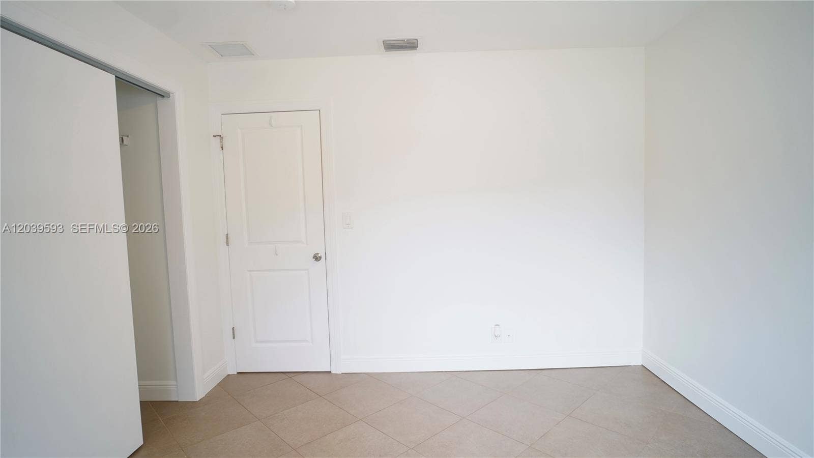 Neutral-toned tile flooring, two-panel interior door, and sliding closet door