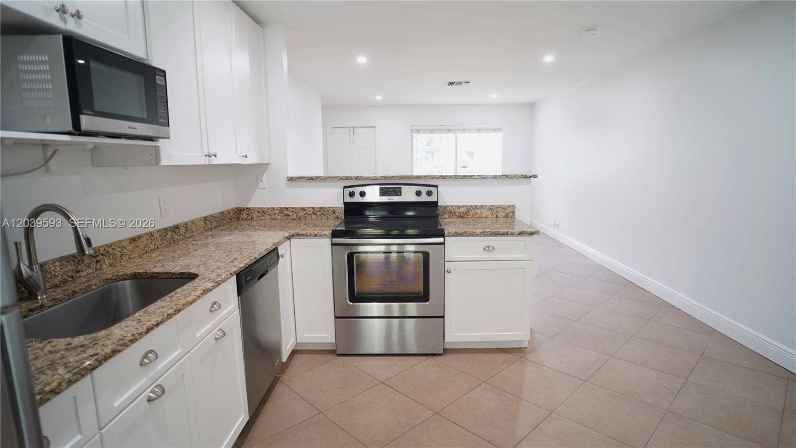 Kitchen featuring white cabinetry, stone-surface countertops, stainless steel appliances, a high-arc faucet, and tiled flooring