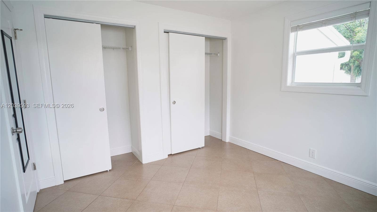 Interior space featuring diagonal-set tile flooring, dual reach-in closets with sliding doors, and a double-hung window