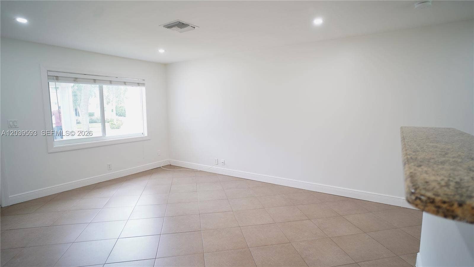 Neutral-toned tile flooring, recessed ceiling lighting, and a single-hung window featuring a horizontal blind