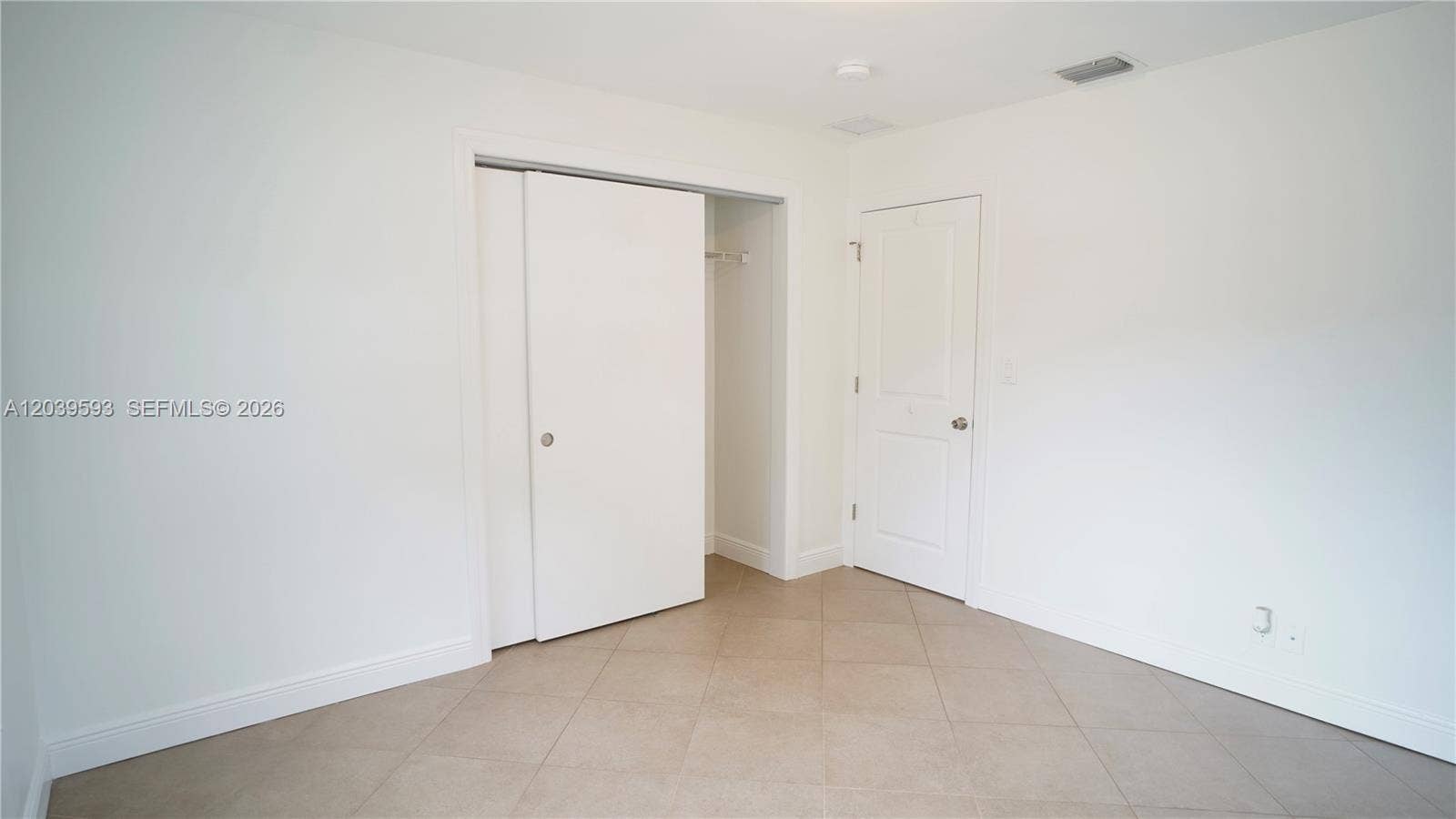 Neutral-toned tile flooring, sliding bypass closet doors, and a solid-core interior swing door
