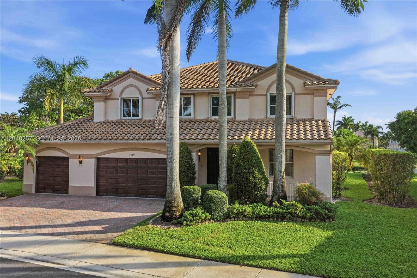 Three-car garage and lush greenery.