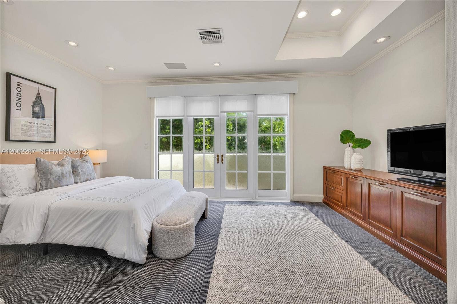 Spacious room featuring a recessed ceiling, grid-patterned glass French doors, built-in wooden cabinetry, recessed lighting, and patterned flooring
