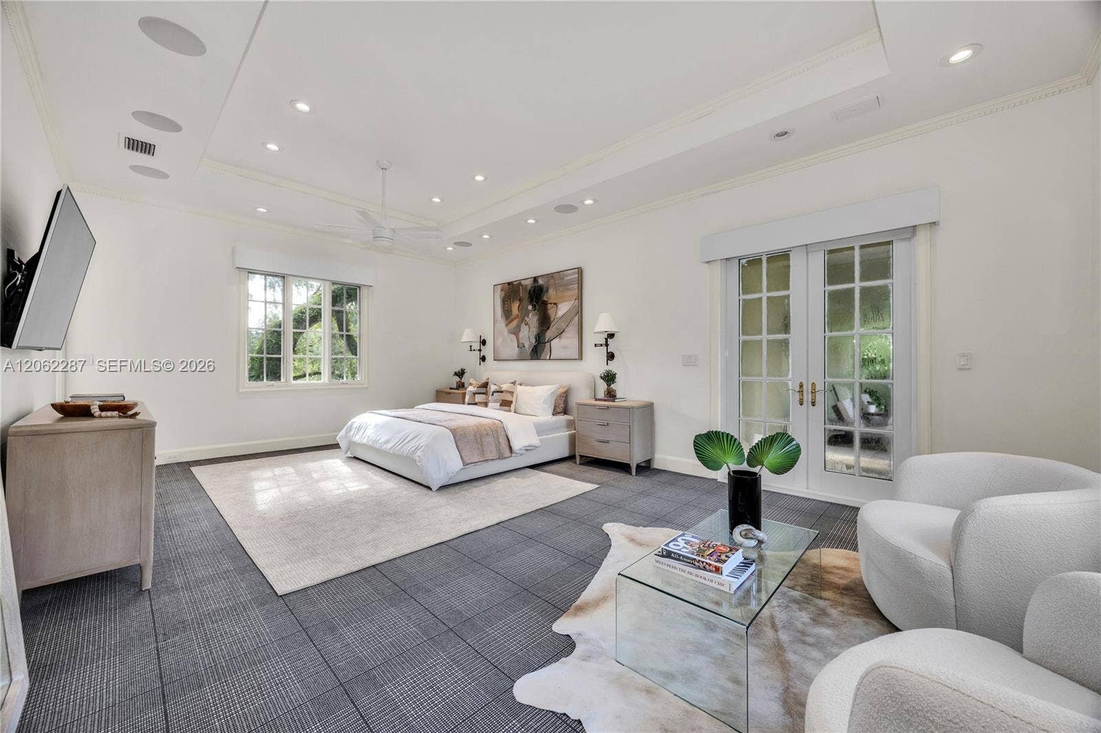 Tray ceiling featuring recessed lighting and a central ceiling fan, expansive grid-patterned carpet flooring, multi-pane window, and French doors